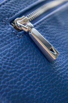 Natural or artificial leather texture. Fragment of a blue bag with a zipper and stitching. Zipper or clasp bag design element. Bovine skin texture with snake. Macro photo, selective focus