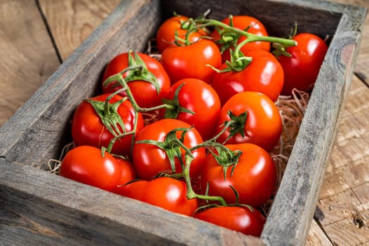 Ripe Red tomatoes in wooden market box. Wooden background. Top view.