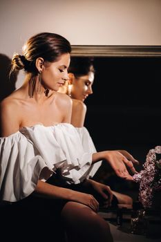 Beautiful girl in the mirror reflection at home. Girl before the holiday near the home mirror.A girl in a white dress with long hair is going to a party at home.