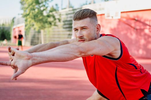 sports man in a red t-shirt on the sports ground doing exercises. High quality photo