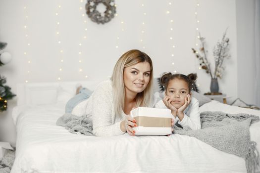 People reparing for Christmas. Mother playing with her daughter. Family is resting in a festive room. Child in a sweater sweater.