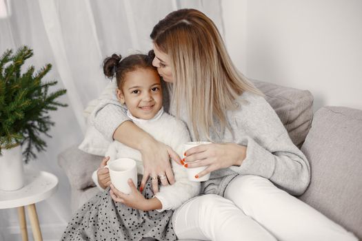 People reparing for Christmas. Mother playing with her daughter. Family is resting in a festive room. Child in a sweater sweater.