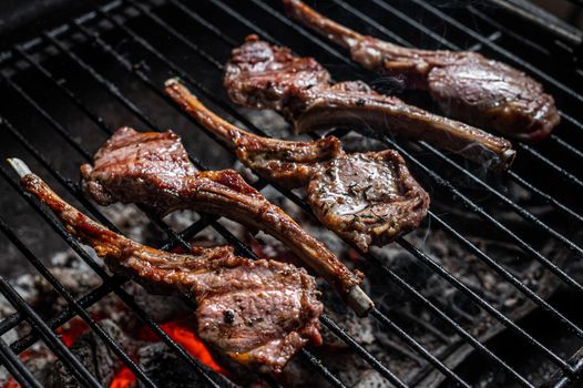 Grilled lamb mutton chop steaks on barbecue, outdoor BBQ grill with fire. Top view.