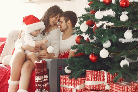 Mother in a white sweater. Family with christmas gifts. Child with parents in a christmas decorations.