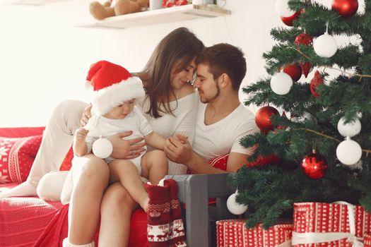 Mother in a white sweater. Family with christmas gifts. Child with parents in a christmas decorations.