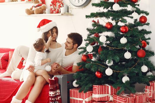 Mother in a white sweater. Family with christmas gifts. Child with parents in a christmas decorations.