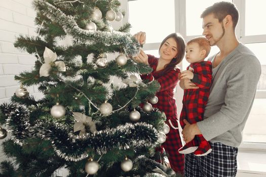 People at home. Family in a pajamas. Mother with husband and child in a Christmas decorations.