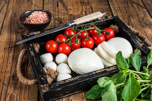 Mozzarella cheese, basil and tomato cherry in wooden tray, Caprese salad. wooden background. Top view.