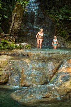 Mom and daughter on a mountain river under a waterfall in the jungle.Turkey