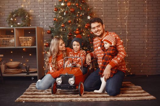 People reparing for Christmas. People playing with their daughter. Family is resting in a festive room. Child in a red dress.