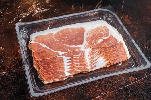 Italian prosciutto crudo or jamon in a vacuum package. Dark background. Top View.