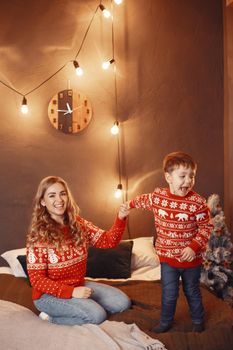 Beautiful mother with child. Family in cristmas atmosphere. Little boy on a bed.