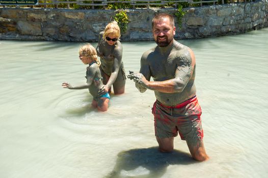 A happy family takes a mud bath at a resort in Turkey.Family wellness in therapeutic mud.