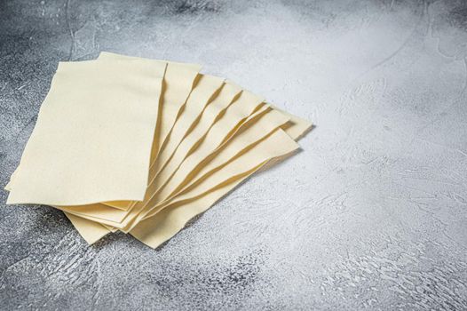 Raw lasagna sheets stack on a kitchen table. White background. Top view. Copy space.