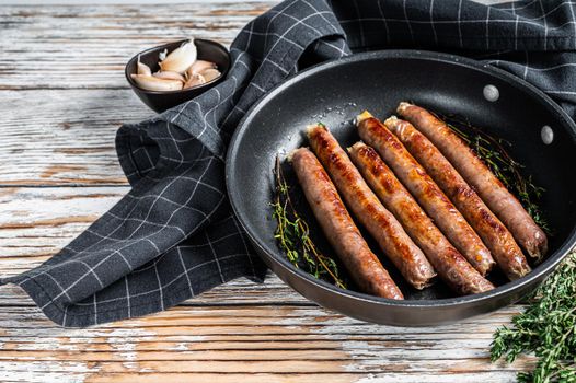 Fried beef and pork meat sausage in a pan with italian herbs and cheese. White wooden background. Top view. Copy space.