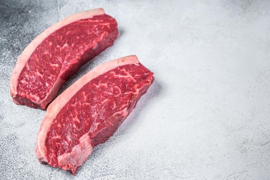 Raw cap rump or top sirloin beef meat steak. White background. Top view. Copy space.