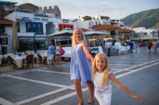 Happy mom and daughter walk along the promenade of Marmaris, Turkey.