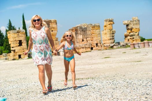 a little girl and her mother walk in the old ruins in the city of Pamukkale. Turkey.