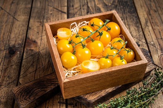 Box with yellow cherry tomato. wooden background. Top view.