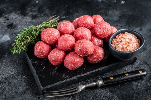 Raw meatballs from minced beef and pork meat with thyme. Wooden background. Top view.