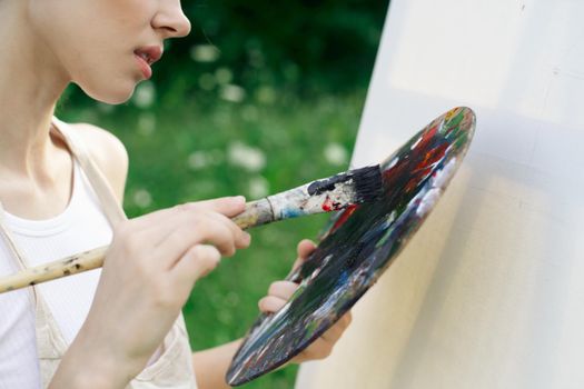 woman artist in white dress paint palette drawing close-up. High quality photo