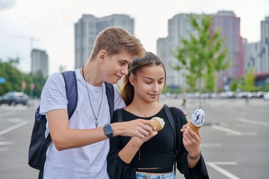 Happy talking couple of teenagers walking together in city, guy and teenage girl with ice cream, friendship, relationship, summer, leisure, lifestyle, adolescence concept
