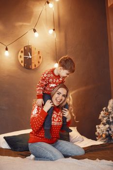 Beautiful mother with child. Family in cristmas atmosphere. Little boy on a bed.