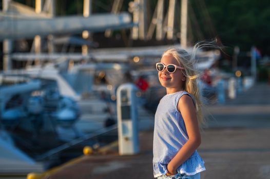 Portrait of a cute smiling little girl with glasses.A girl in shorts and a blue T-shirt at sunset by the sea.Turkey.