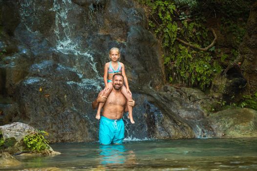 Father and daughter at a waterfall in the jungle. Traveling in nature near a beautiful waterfall, Turkey.