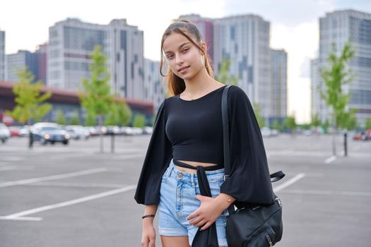 Single portrait of beautiful smiling fashionable teenage girl 14, 15 years old looking at camera, adolescence, young people, youth, city, urban style background