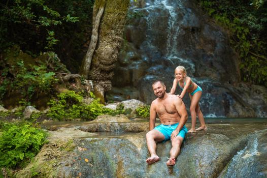 Father and daughter at a waterfall in the jungle. Traveling in nature near a beautiful waterfall, Turkey.