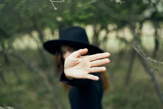 woman in a black hat gesturing with her hands witch magic fantasy. High quality photo