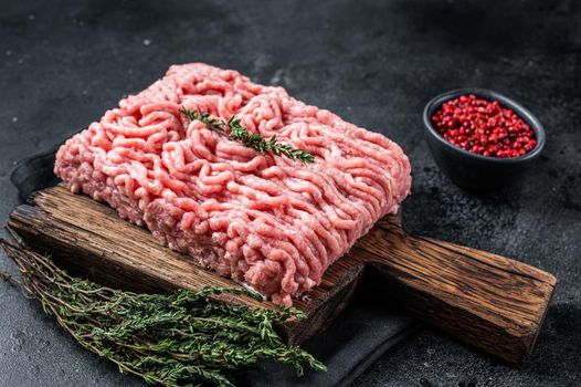 Ground chicken or turkey raw meat on wooden board. Black background. Top View.