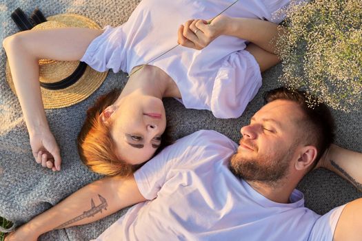 Portrait of beautiful happy couple in 30s 40s. Top view of smiling faces of man and woman lying together in sunset sunlight. Middle-aged people in love, relationship, relaxation, happiness, lifestyle