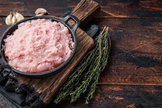 Uncooked Raw minced chicken and turkey meat in a pan with herbs. Dark wooden background. Top view. Copy space.