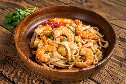 Udon stir-fry noodles with shrimp prawns in a wooden bowl. wooden background. Top view.