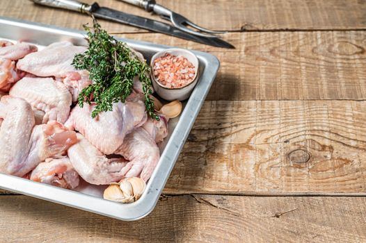 Raw chicken wings Poultry meat ready for cooking with herbs. Wooden background. Top view. Copy space.