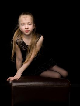 Beautiful little girl in a dance suit posing in the studio. Creative development concept of a child. On a black background.