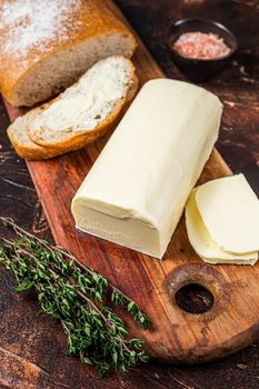 Sliced toast bread with butter spread on a wooden cutting board. Dark background. Top view.