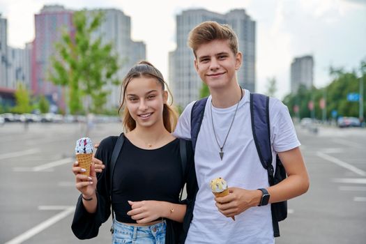 Couple of happy teenagers looking at the camera, guy and teenage girl with ice cream, friendship, relationship, summer, leisure, lifestyle, adolescence concept