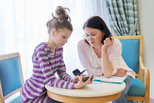 Preteen child girl at meeting with therapist, social worker, counselor in office, kid showing his smartphone to teacher. Psychology, education, therapy, mental health, children concept