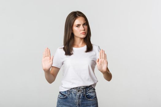 Serious displeased young woman showing stop gesture, saying no.