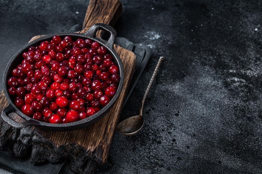 Red fresh Cranberry berry in a pan. Black background. Top view. Copy space.