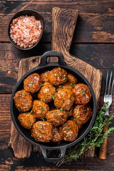 Meatballs in tomato sauce from beef and pork meat with thyme in rustic pan. Dark background. Top view.