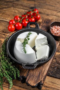 Fresh Ricotta cream Cheese in a pan with basil and tomato. wooden background. Top view.