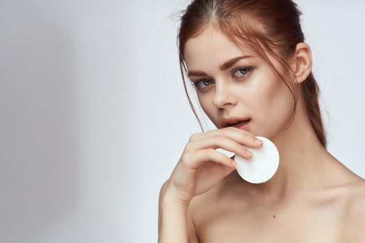 woman with bare shoulders cotton pad clean skin light background. High quality photo