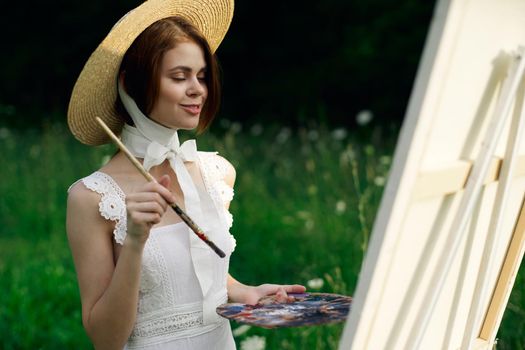 Woman in white dress artist easel painting nature landscape. High quality photo