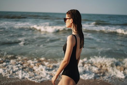 woman in black swimsuit walking on the beach ocean summer. High quality photo