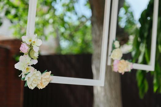 Decorating events, close-ups of decor details. Wooden white frames decorated with flowers in the outdoor garden