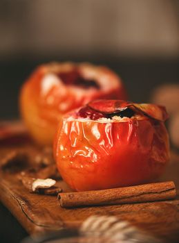 baked apples with cottage cheese with berries and nuts, topped with honey and sprinkled with cinnamon. on a wooden surface in a rustic style